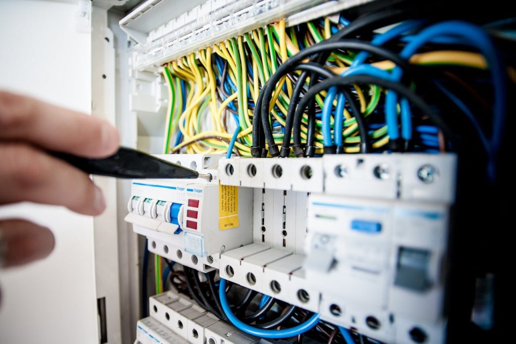 Home Hand of electrician working on a circuit breaker panel with colorful wires, ensuring safe electrical connections.
